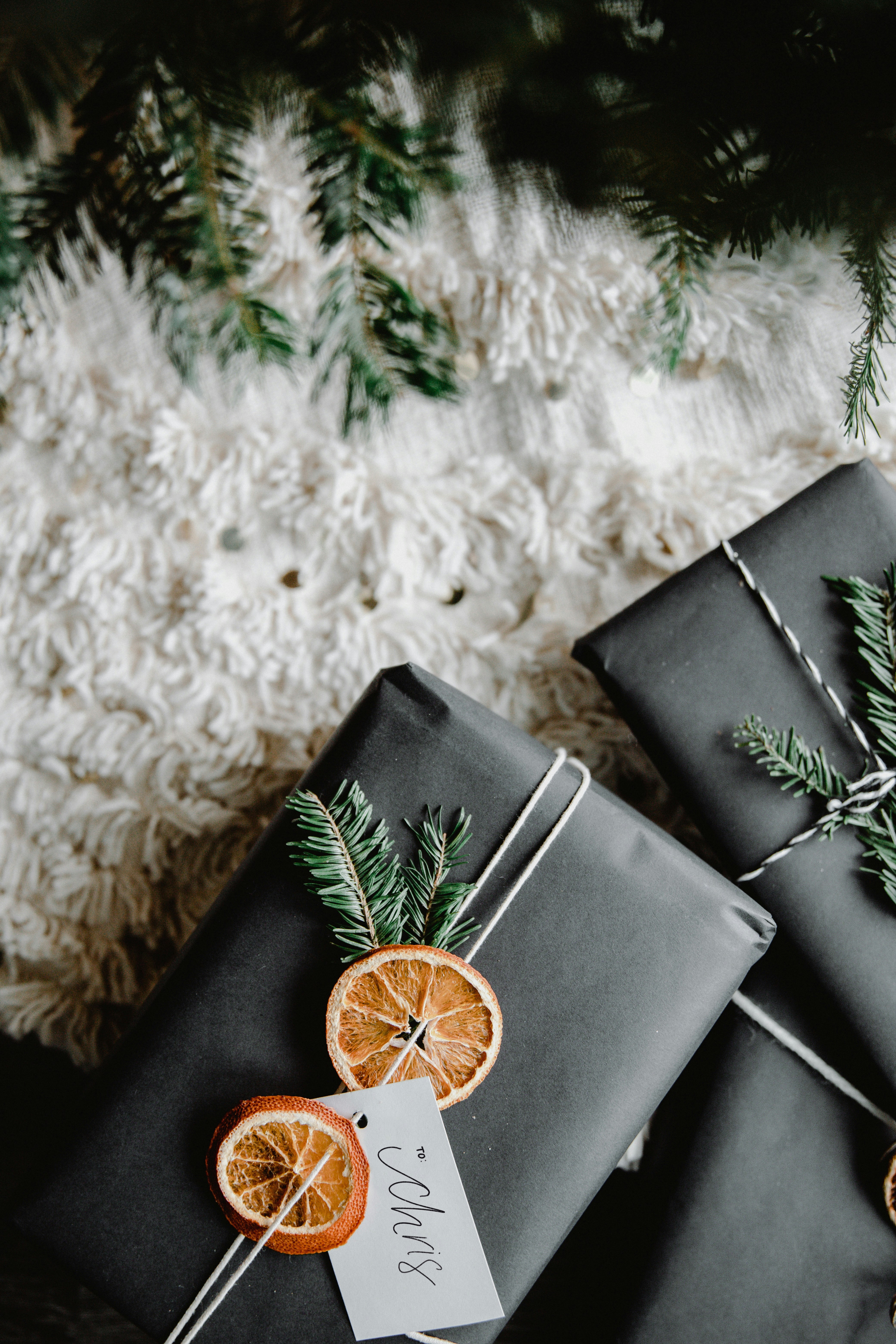 non toxic gift guide for her holiday gifts wrapped in black paper with dried orange and evergreen